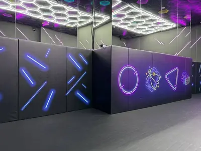 Стильная игровая зона с чёрными стеновыми протекторами, неоновым декором и шестиугольными светильниками