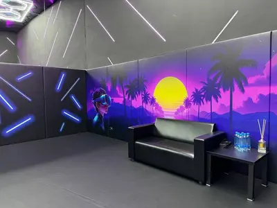 Игровая зона с чёрными протекторами, VR-муралом тропического заката, диваном и серым полом