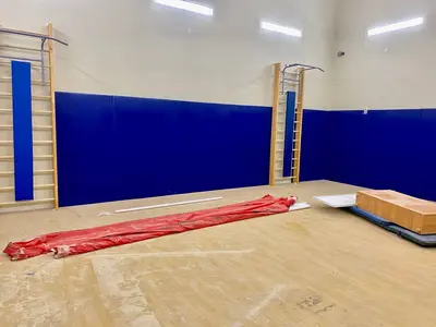 Спортзал школы №7 Няндома с синими стеновыми протекторами, шведскими стенками и деревянным полом