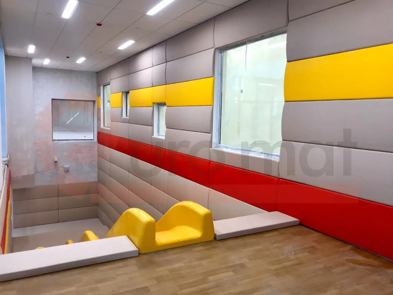 Разноцветные стеновые протекторы (бежевые, жёлтые, красные) в детском спортзале с горкой и скалодромом