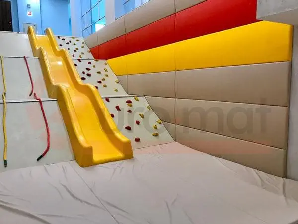 Бежевые и красные стеновые протекторы у основания горки со скалодромом и страховочным матом