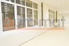 Белые стеновые протекторы вдоль оконной стены школьного зала с бежевым напольным покрытием