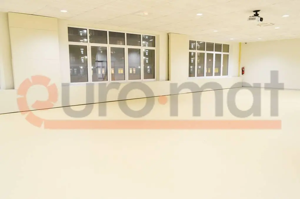 Белые стеновые протекторы и бежевое напольное покрытие в школьном зале с проектором на потолке