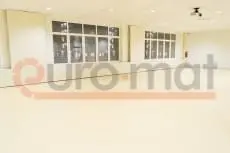 Белые стеновые протекторы и бежевое напольное покрытие в школьном зале с проектором на потолке