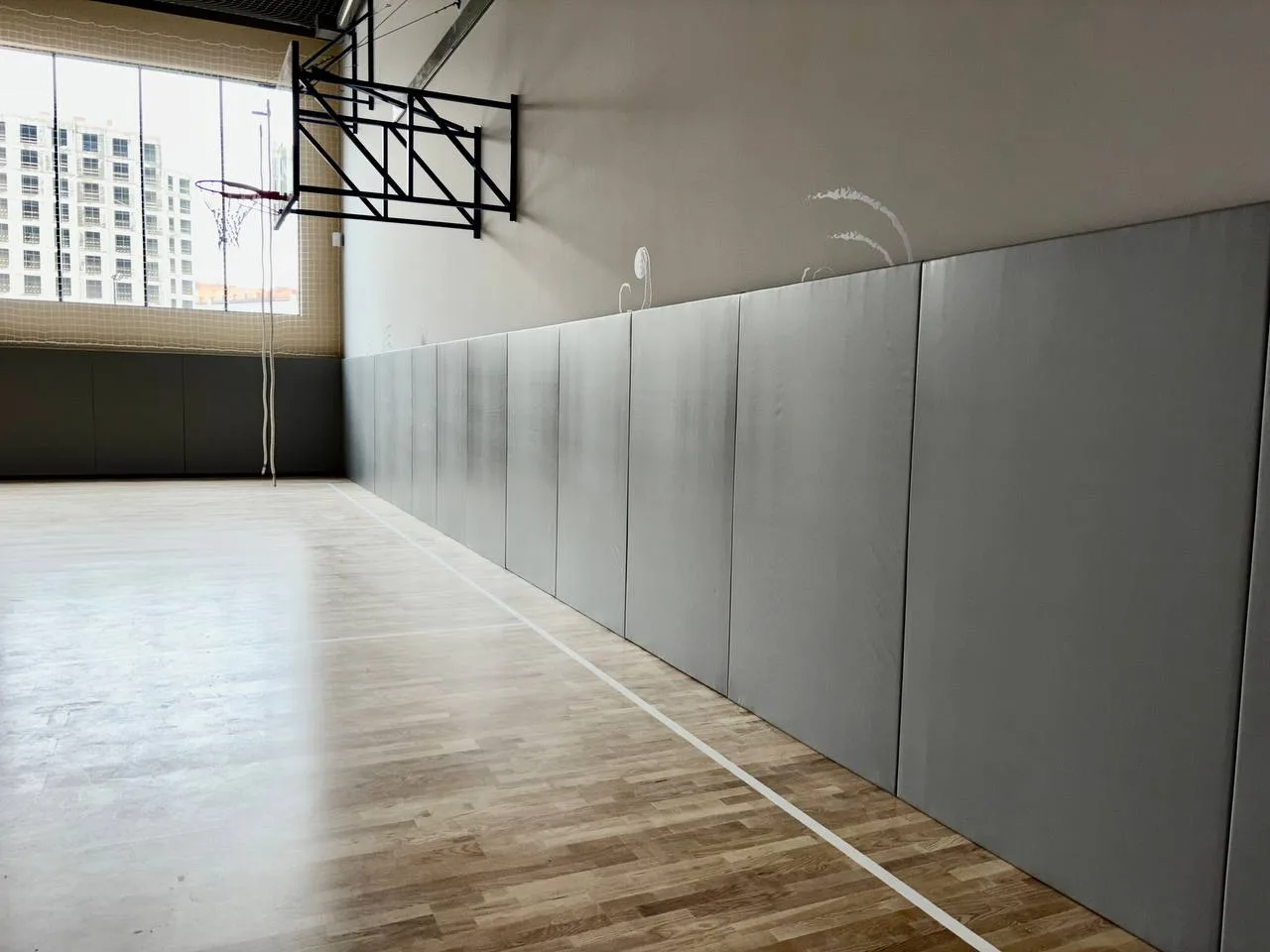 Серые стеновые протекторы в современном спортзале новой школы Санкт-Петербурга с паркетным полом