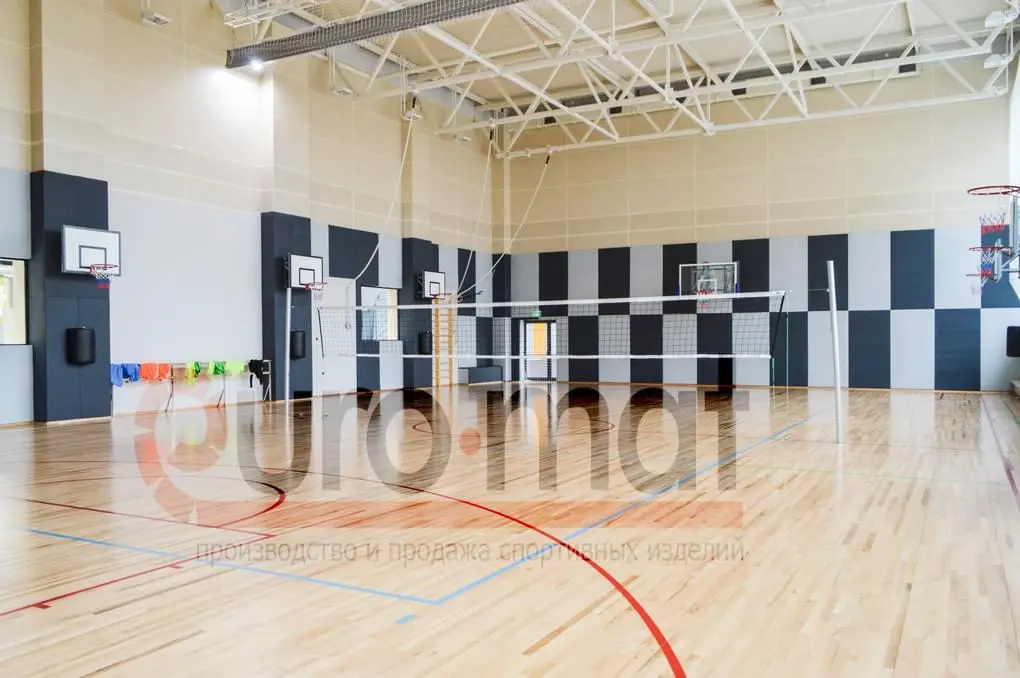 Шахматные стеновые протекторы серо-белые в школьном спортзале с волейбольной сеткой