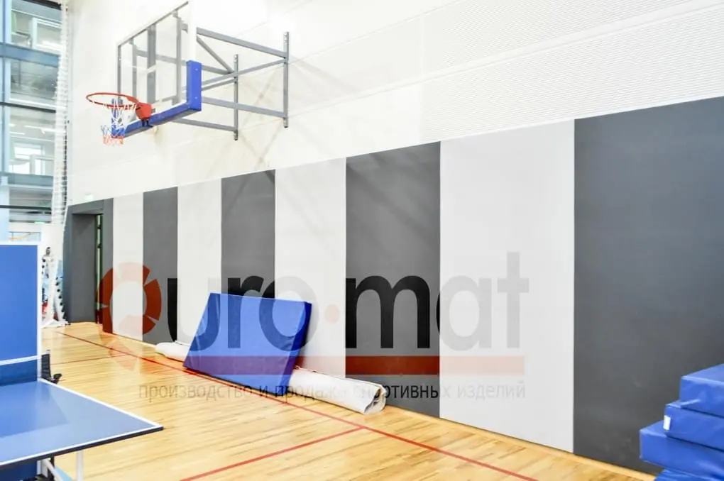 Стеновые протекторы серые и белые вертикальными полосами в школьном спортзале