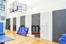 Стеновые протекторы серые и белые вертикальными полосами в школьном спортзале