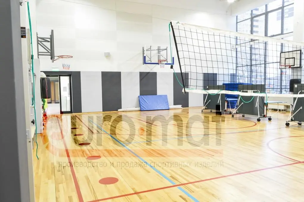 Стеновые протекторы серые и белые в школьном спортзале с баскетбольными щитами