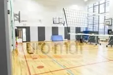 Стеновые протекторы серые и белые в школьном спортзале с баскетбольными щитами