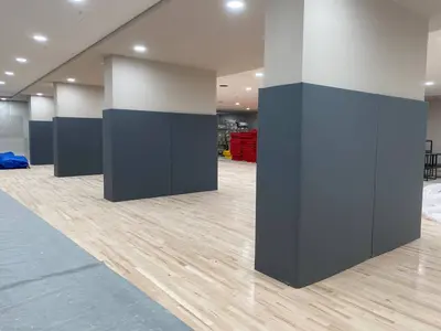 Серые защитные протекторы на квадратных бетонных колоннах в зале Дворца единоборств Сочи, паркетный пол