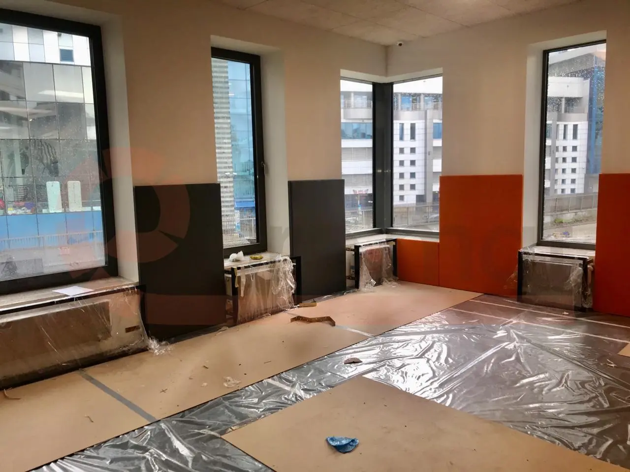 Установка оранжевых и графитовых стеновых протекторов у окон спорткомплекса — процесс монтажа