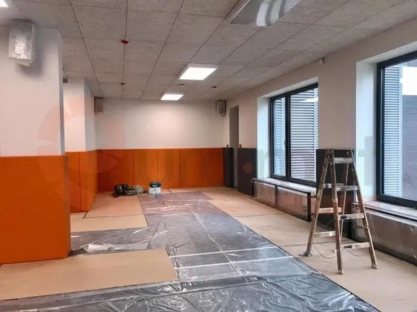 Оранжевые и графитовые стеновые протекторы в спорткомплексе — панели вдоль стен, стремянка у окна