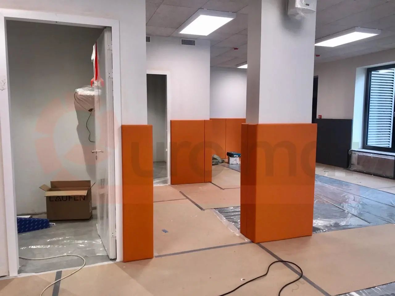 Оранжевые стеновые протекторы на колоннах спорткомплекса — панели стоят перед установкой на колонну