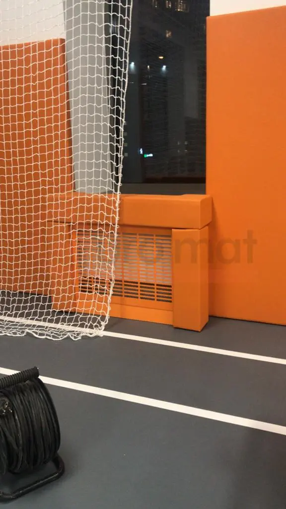 Оранжевые стеновые протекторы с вырезом под радиатор в спорткомплексе, серый спортивный пол с разметкой