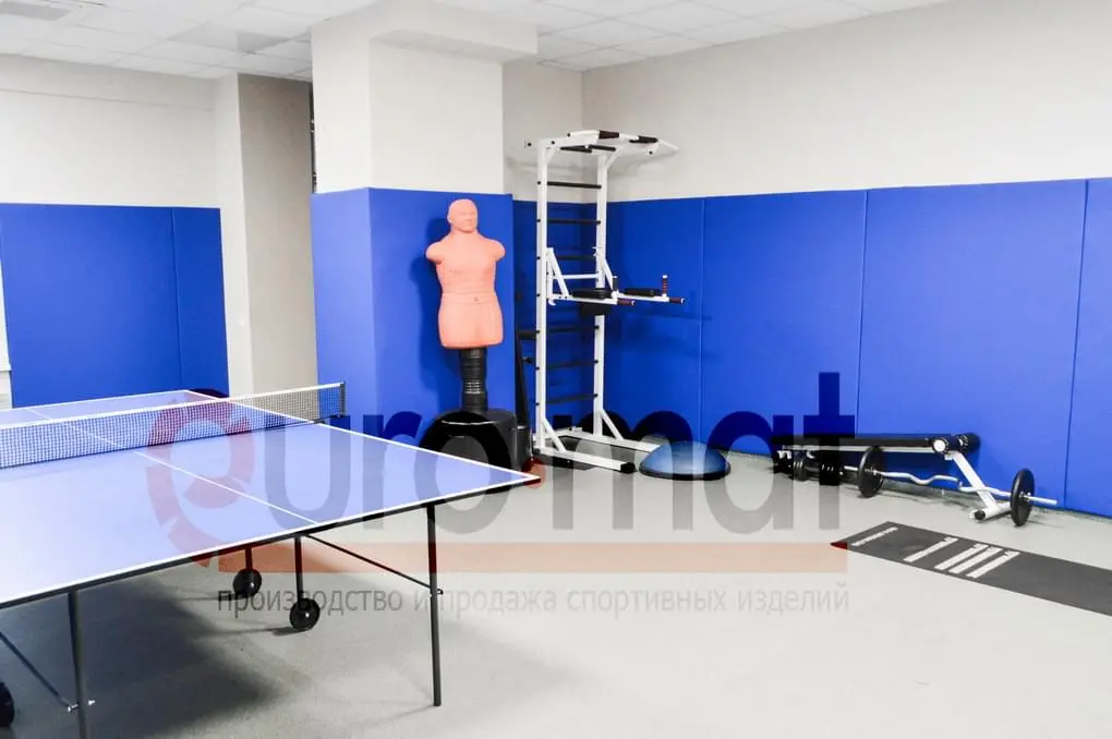 Синие стеновые протекторы в тренажёрном зале с манекеном для бокса и теннисным столом