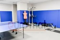 Синие стеновые протекторы в тренажёрном зале с манекеном для бокса и теннисным столом