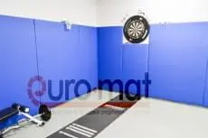 Синие стеновые протекторы в углу зала с дартсом и силовой скамьёй