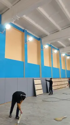Широкий вид на спортзал Владикавказа с серыми протекторами, рабочие монтируют панели на OSB-основу