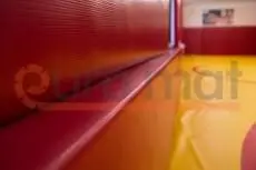 Красные стеновые протекторы крупным планом, жёлтый борцовский ковёр на заднем плане