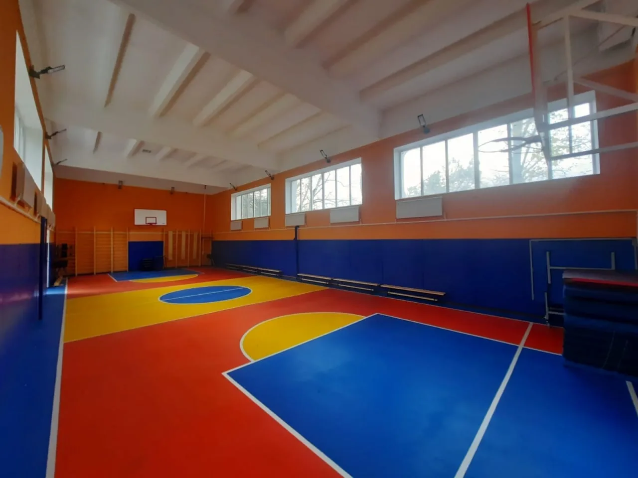 Синие стеновые протекторы в спортзале Железноводска с ярким баскетбольным полом красного, синего и жёлтого цвета