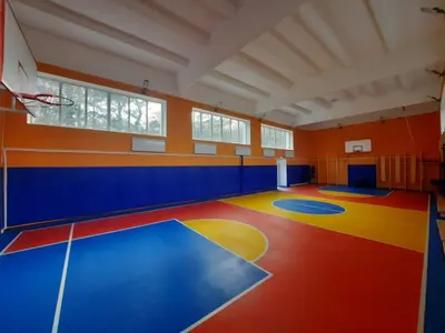Спортзал Железноводска: синие протекторы, баскетбольные щиты, яркий пол с разметкой и оранжевые стены