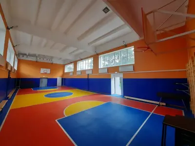 Вид на вход спортзала Железноводска: синие протекторы, разноцветный пол, баскетбольные щиты и оранжевые стены