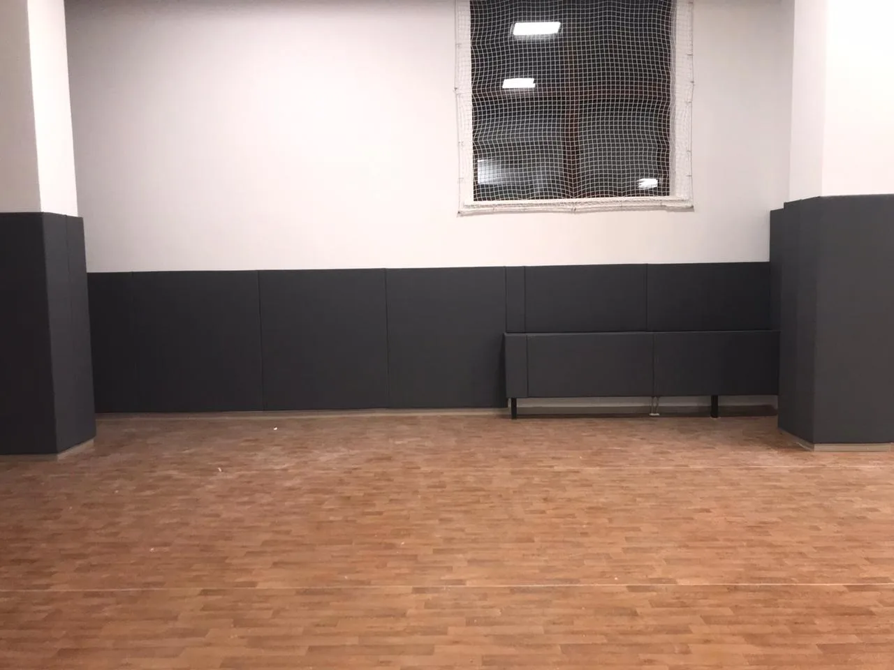 Материал и решение: тёмно-серые стеновые протекторы и защитная сетка на окне спортзала