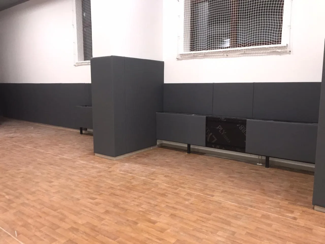 Комплексная защита: тёмно-серые стеновые протекторы на стене и обшитая колонна с защитными сетками