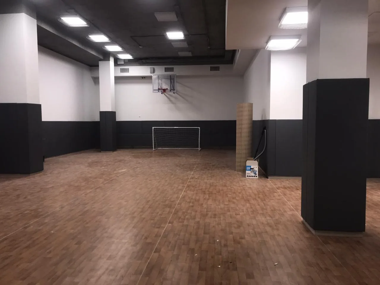 Готово: общий вид спортзала Кембриджской школы с полным покрытием тёмно-серыми стеновыми протекторами и обшитыми колоннами