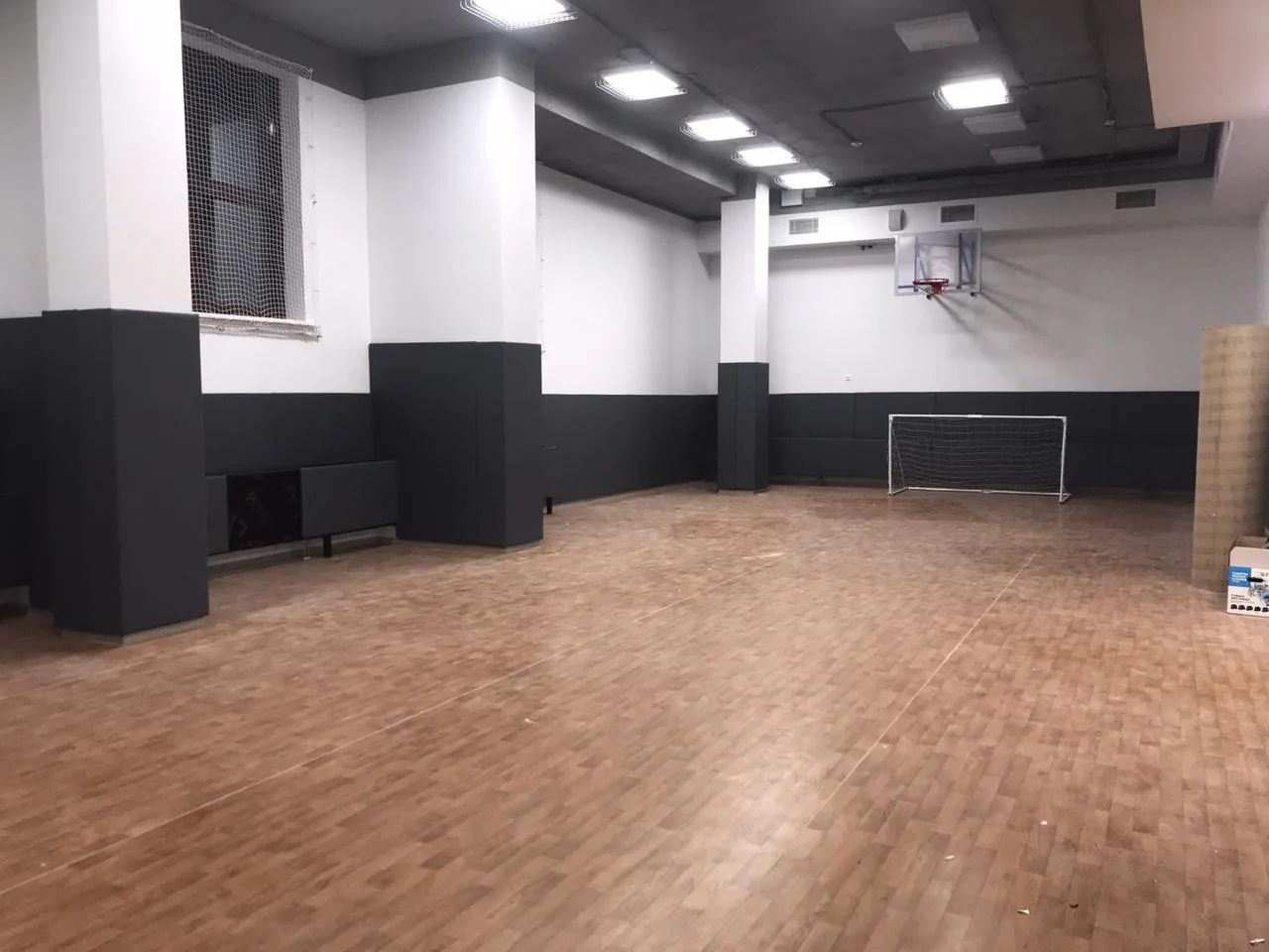 Фото 9: панорама спортзала с тёмно-серыми протекторами, обшитыми колоннами и баскетбольным щитом