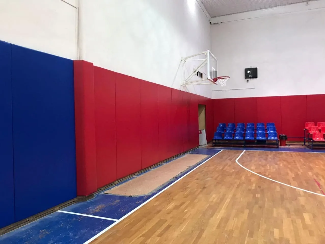 Угол баскетбольного зала ЦСКА с синими и красными протекторами, кольцом и зрительскими креслами