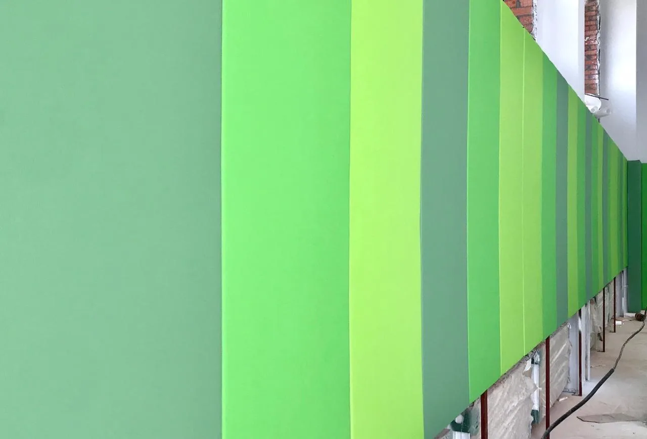 Крупный план зелёных стеновых протекторов в разных оттенках на стене зала