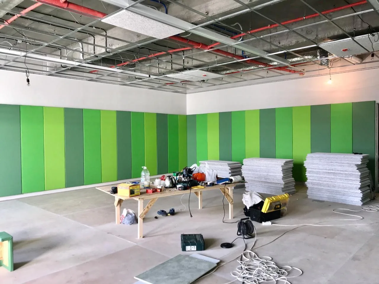 Установленные зелёные протекторы в два ряда на стене под окном спортзала