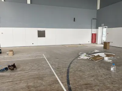 Светлые стеновые протекторы вдоль стены школьного зала с окном и строительными материалами