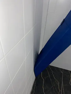 Крупный план синего протектора на наклонной металлической балке у кафельной стены