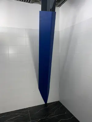 Синий протектор на угловой металлической колонне в углу помещения с кафелем