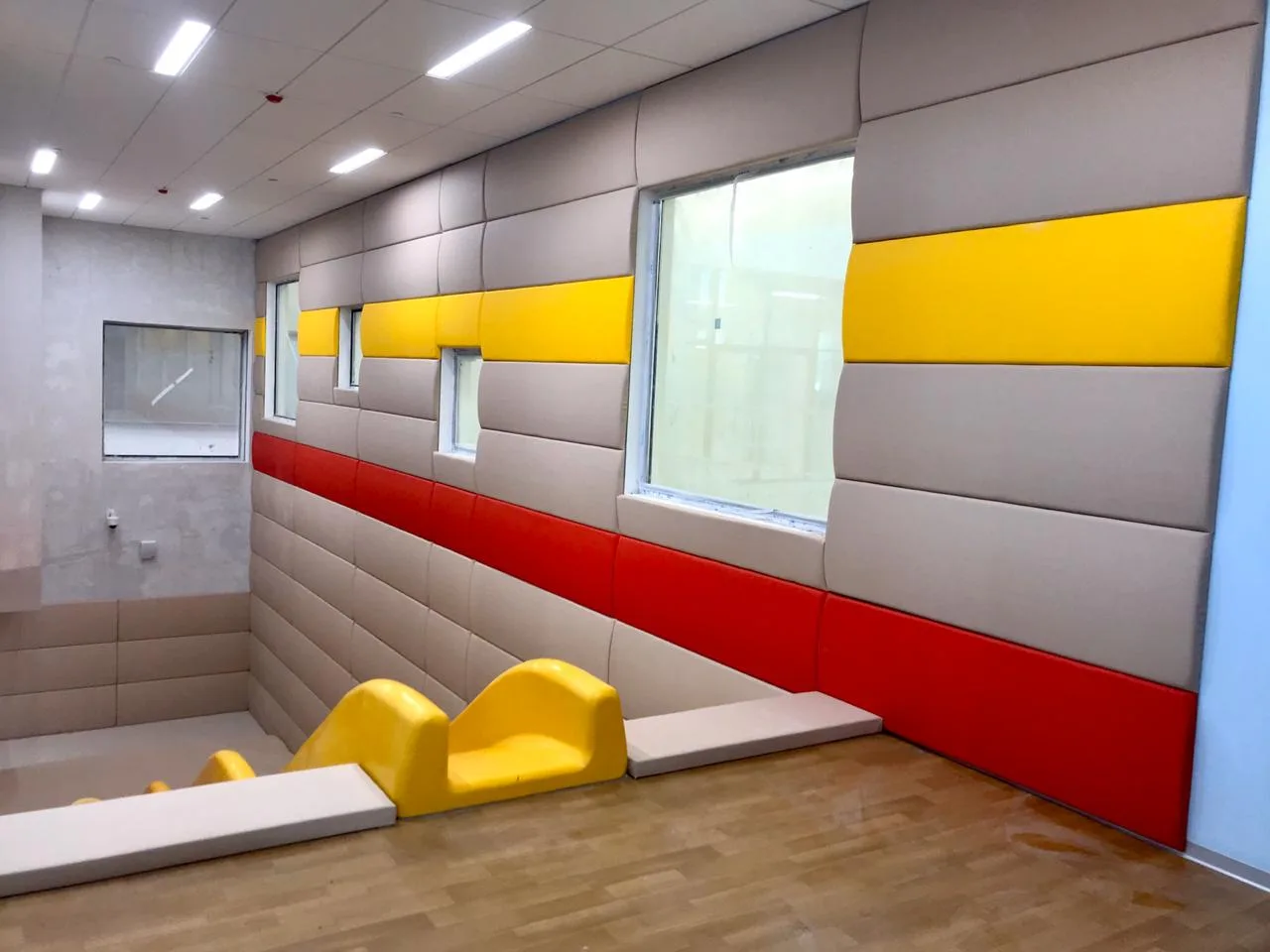 Игровая зона с бежевыми, красными и жёлтыми протекторами, горкой и жёлтыми стульчиками