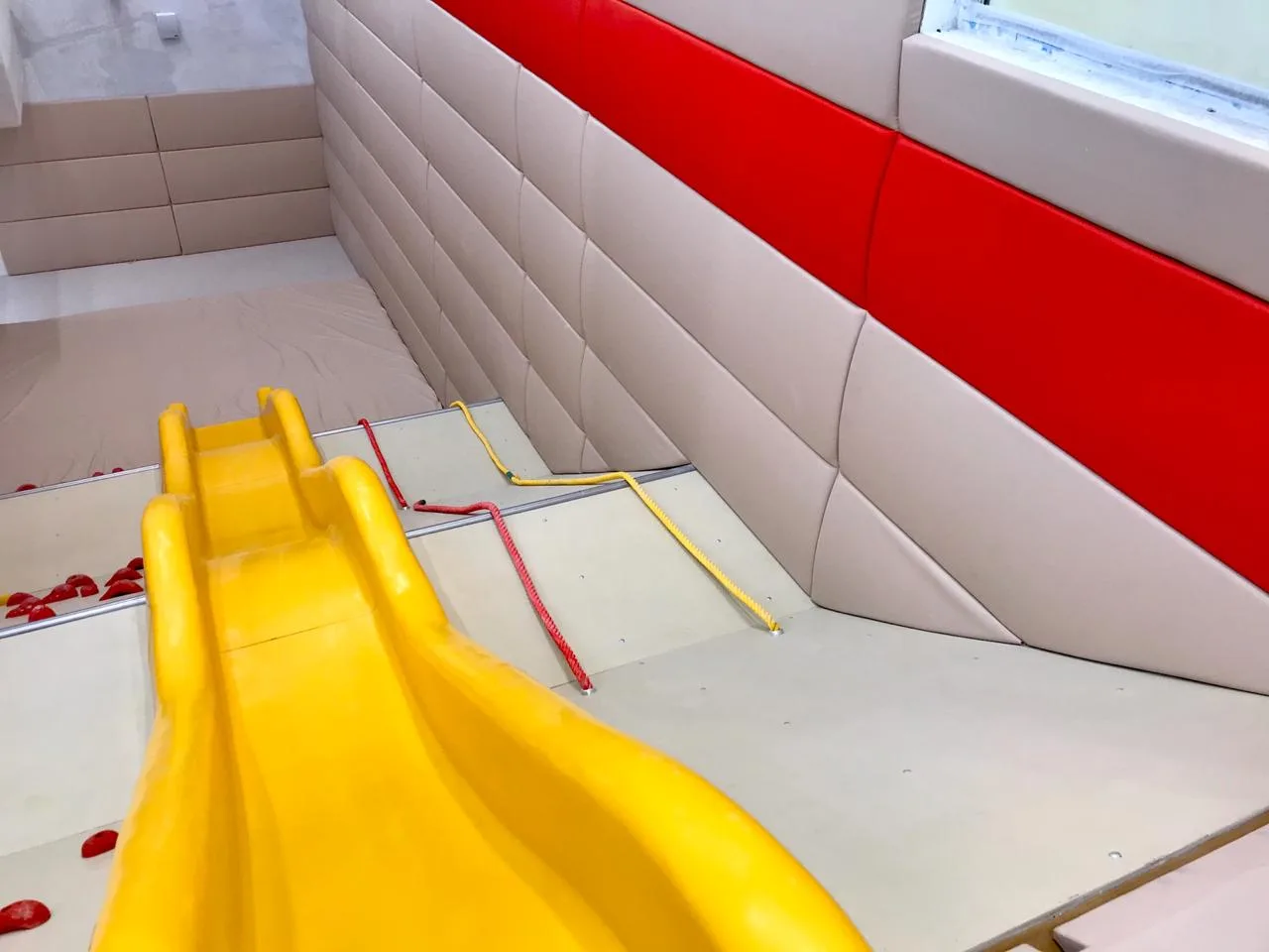 Жёлтая горка и бежево-красные выпуклые протекторы на стенах вид сверху крупным планом