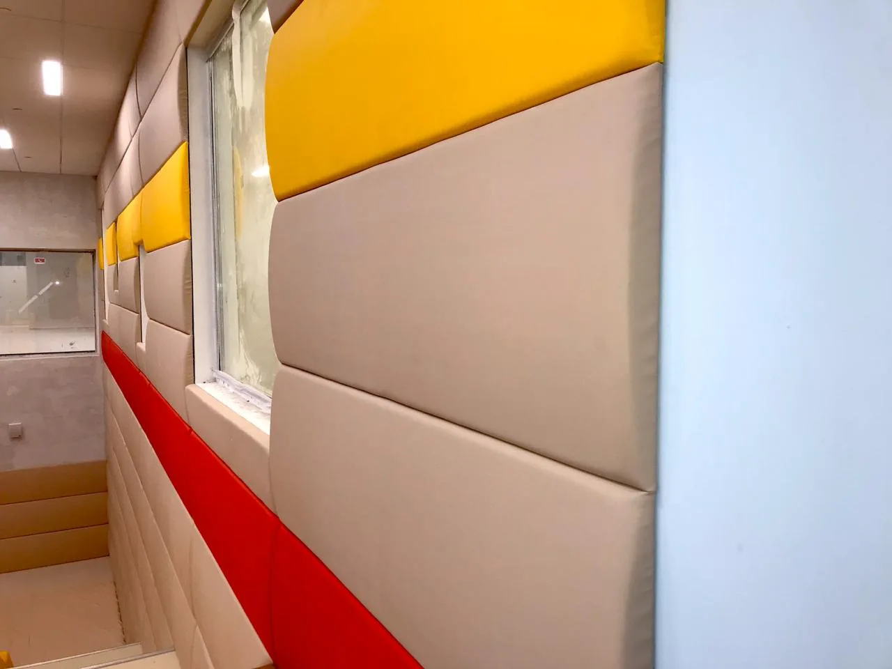 Выпуклые бежевые и жёлтые стеновые протекторы вокруг окна крупным планом в игровой зоне