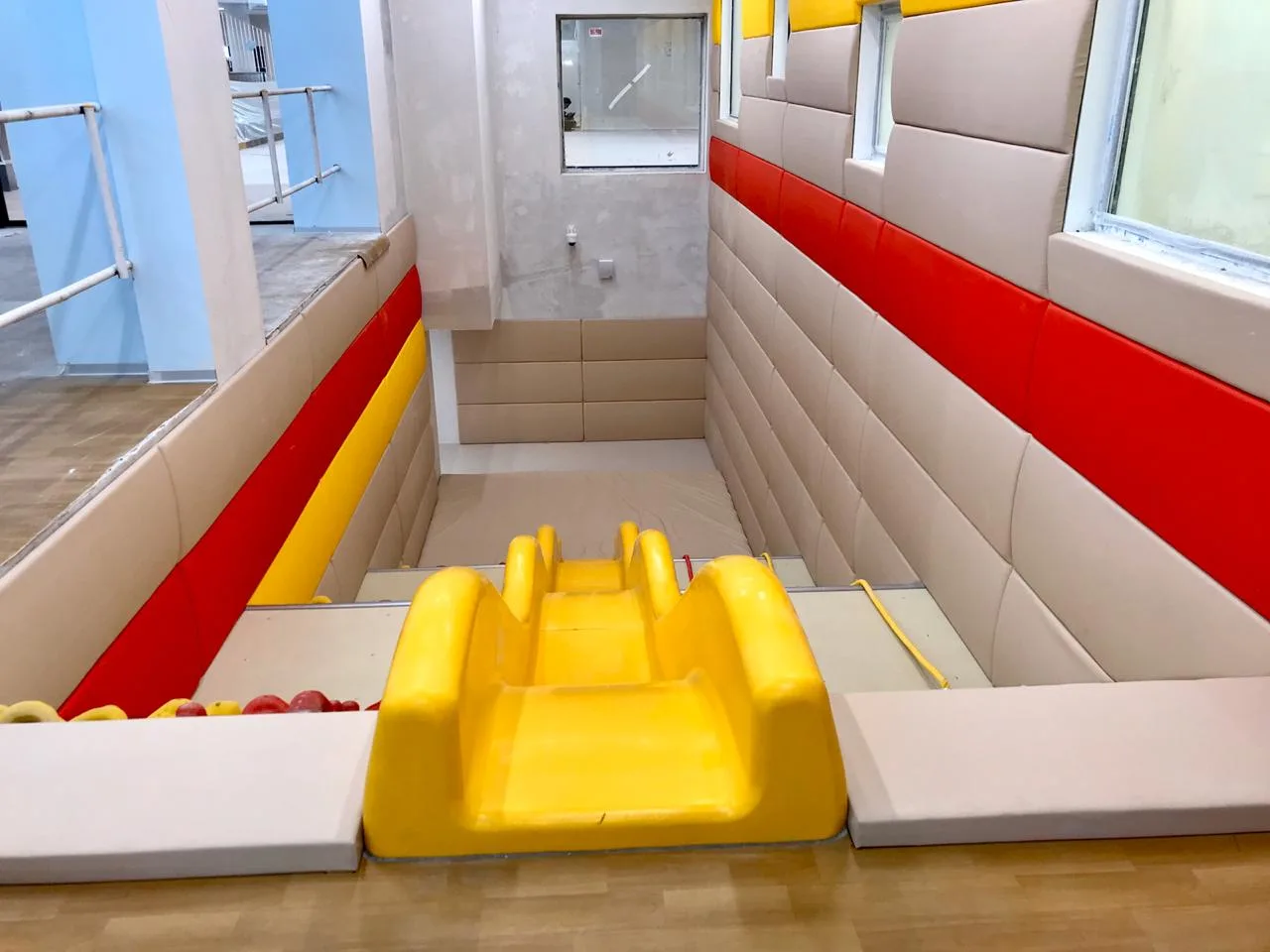 Жёлтая двойная горка и бежево-красные выпуклые протекторы в игровой зоне вид сверху