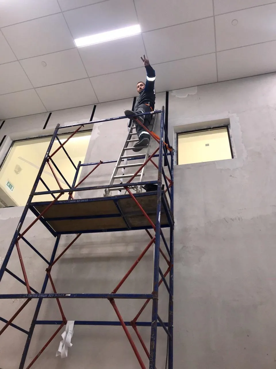 Монтажник на строительных лесах при монтаже стеновых протекторов в игровой зоне