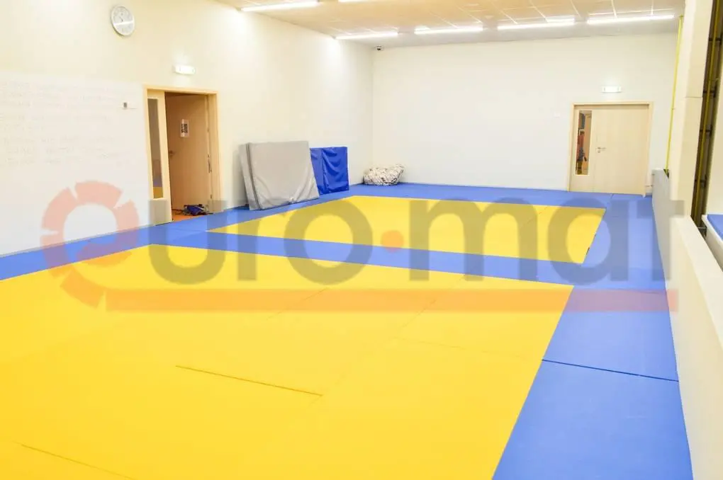 Татами жёлтого и синего цвета уложены на полу зала дзюдо с видимыми стыками пазлов