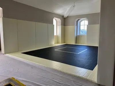 Чёрные татами и бежевые стеновые протекторы в частном зале, вид с угла